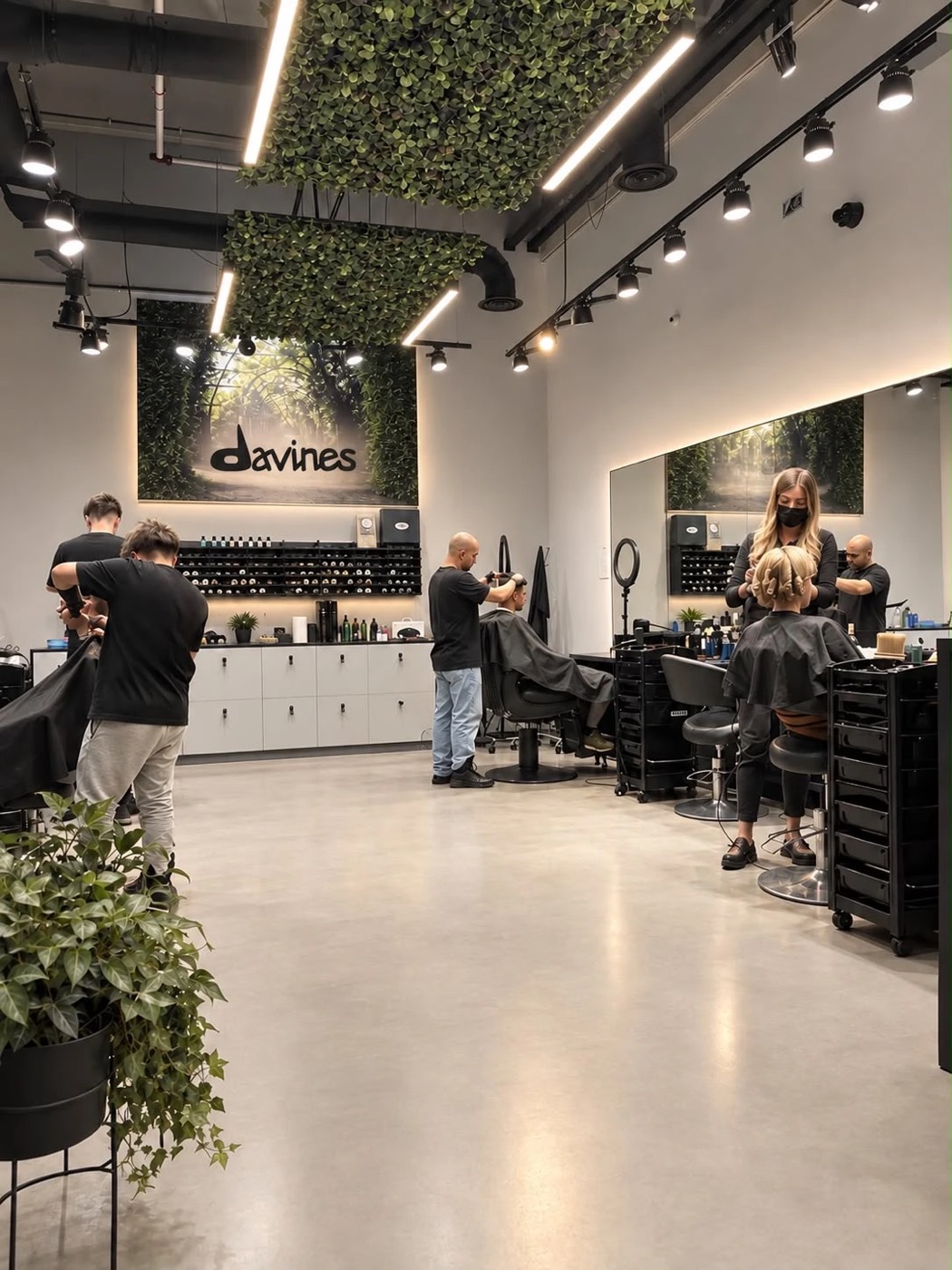 Stiliști la lucru în salonul Headen din Auchan Iris, sub peretele verde Davines